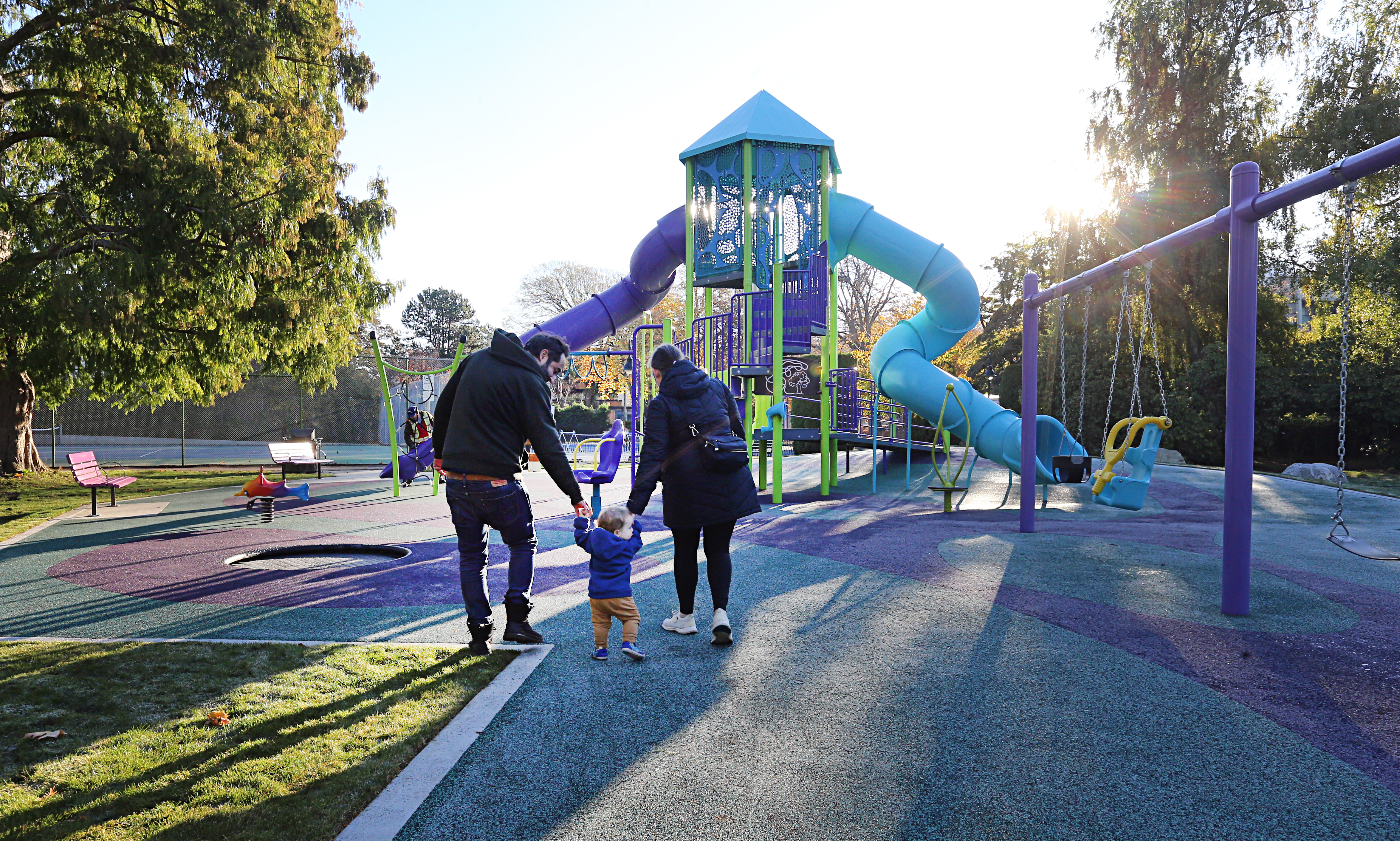 a family with a small child walking to a jungle gym 
